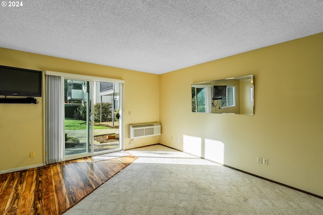 unfurnished room featuring an AC wall unit, a textured ceiling, and wood-type flooring