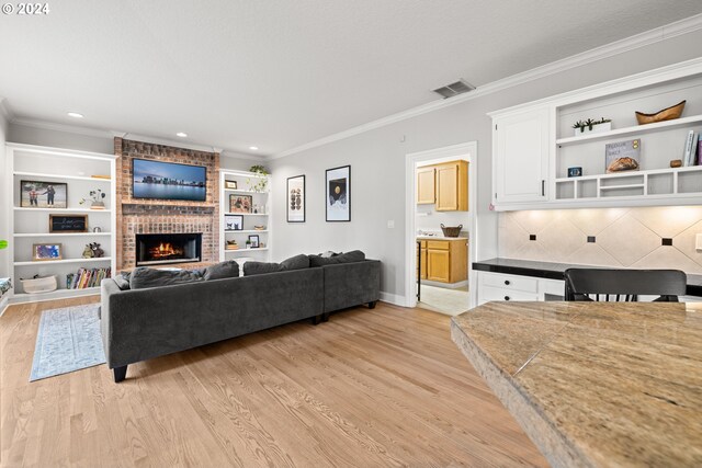 living room featuring a fireplace, crown molding, and light hardwood / wood-style flooring