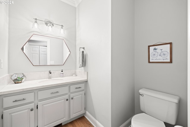 bathroom featuring vanity, hardwood / wood-style flooring, toilet, and ornamental molding