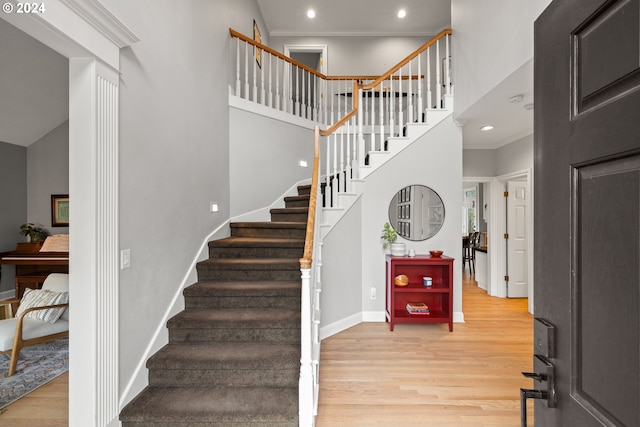 staircase with hardwood / wood-style flooring and ornamental molding