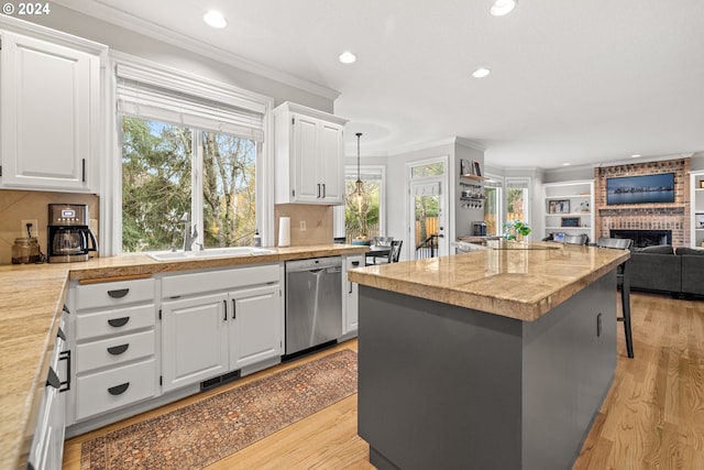 kitchen with a fireplace, pendant lighting, white cabinets, and stainless steel appliances