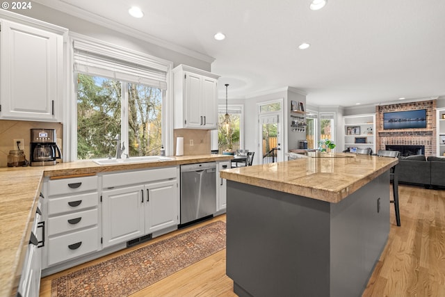 12635 SW 61st Pl, Portland, OR 97219 - kitchen featuring stainless steel dishwasher, a sink, a fireplace, crown molding, and a kitchen island