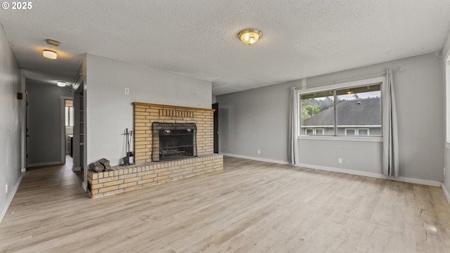 976 E St, Coos Bay, OR 97420 - unfurnished living room with wood finished floors, a textured ceiling, a brick fireplace, and baseboards