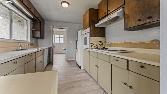 976 E St, Coos Bay, OR 97420 - kitchen featuring under cabinet range hood, white appliances, light countertops, a sink, and light wood-style flooring