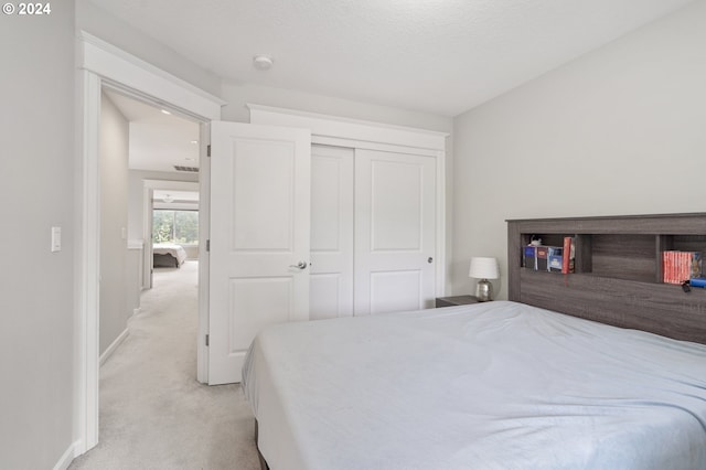 bedroom featuring light carpet, a textured ceiling, and a closet