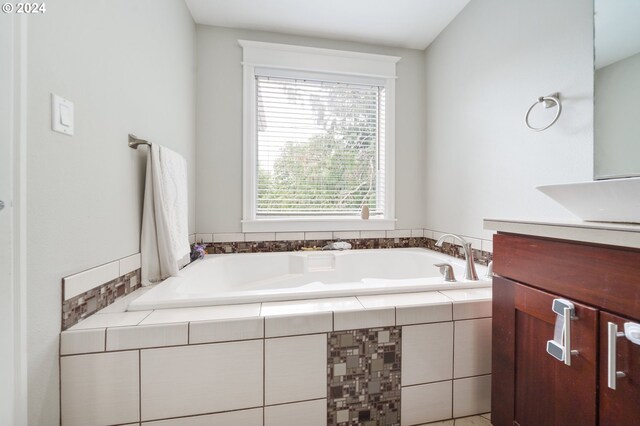 bathroom featuring tiled bath and vanity