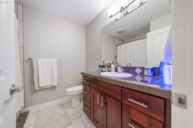 bathroom featuring tile patterned flooring, toilet, and vanity