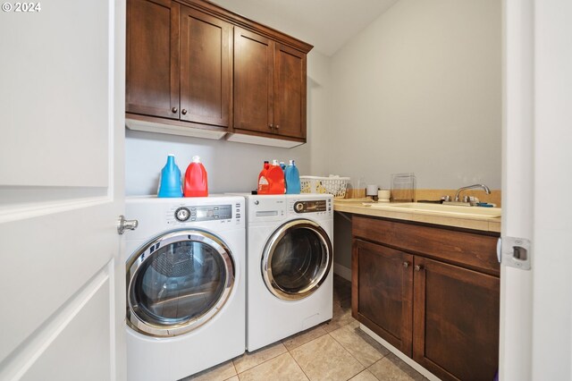 clothes washing area featuring light tile patterned floors, sink, washing machine and clothes dryer, and cabinets