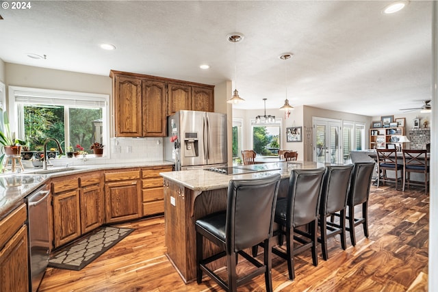 kitchen featuring light hardwood / wood-style flooring, stainless steel appliances, a kitchen breakfast bar, a center island, and ceiling fan