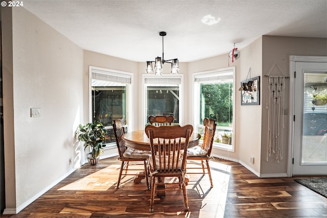 dining space featuring a textured ceiling, an inviting chandelier, and dark hardwood / wood-style floors