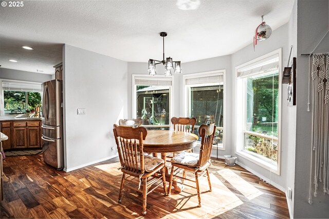 dining room with plenty of natural light, dark hardwood / wood-style floors, sink, and an inviting chandelier