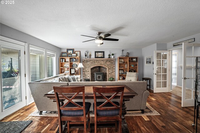 dining area with a fireplace, french doors, dark hardwood / wood-style floors, ceiling fan, and a textured ceiling