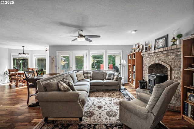 living room featuring french doors, a brick fireplace, dark hardwood / wood-style flooring, ceiling fan, and a textured ceiling