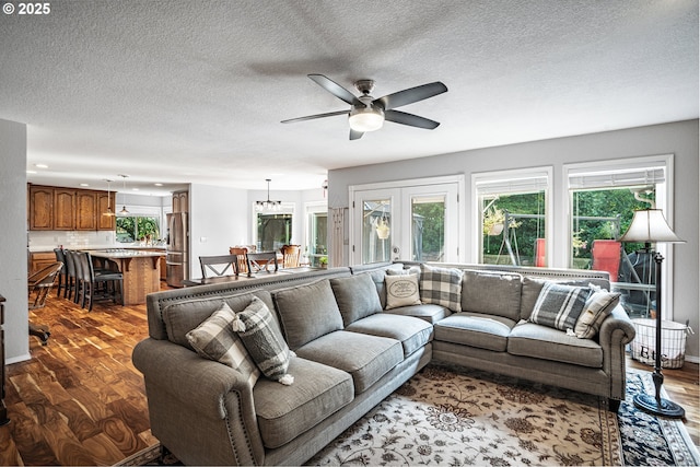 living area with a ceiling fan, french doors, a textured ceiling, and wood finished floors