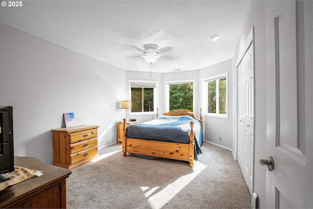 carpeted bedroom featuring ceiling fan, visible vents, baseboards, and a closet