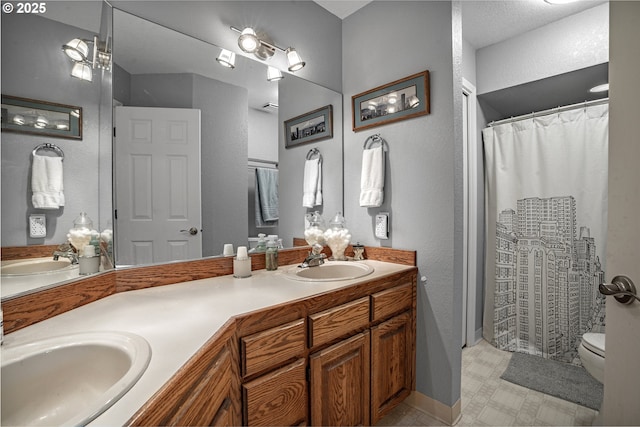 full bathroom featuring a sink, toilet, and double vanity