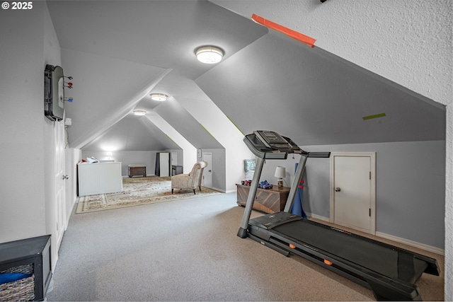 exercise room with carpet floors and vaulted ceiling