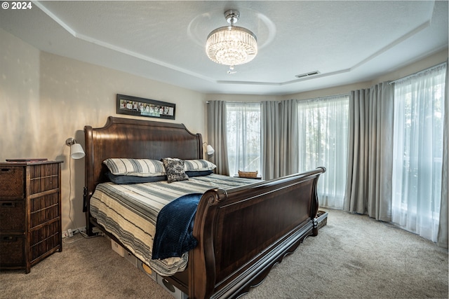 bedroom with a tray ceiling, a textured ceiling, an inviting chandelier, and carpet flooring