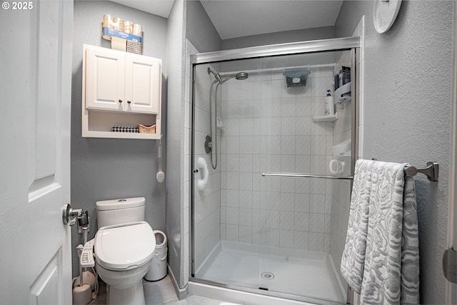 bathroom featuring a textured wall, a stall shower, and toilet