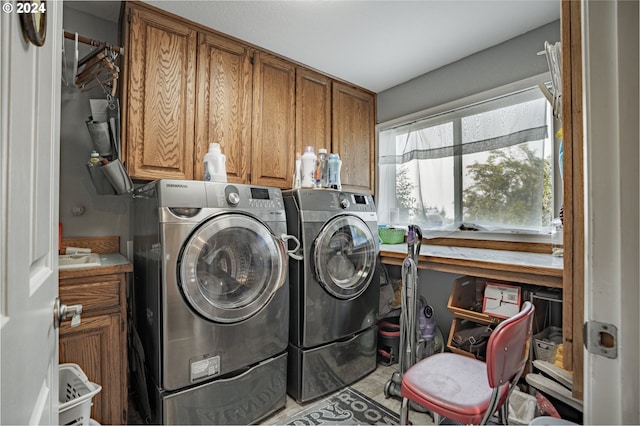 clothes washing area with washer and dryer and cabinets