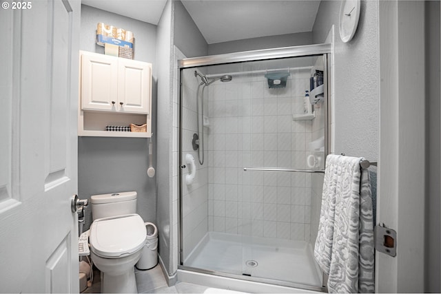 full bathroom with a textured wall, a shower stall, and toilet