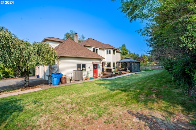 rear view of house with roof with shingles, a yard, a chimney, a gazebo, and central AC unit