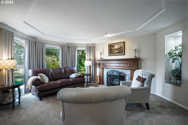 carpeted living room with a tray ceiling, a textured ceiling, and a brick fireplace