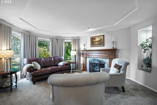 carpeted living room with a textured ceiling, a tray ceiling, a fireplace, and baseboards