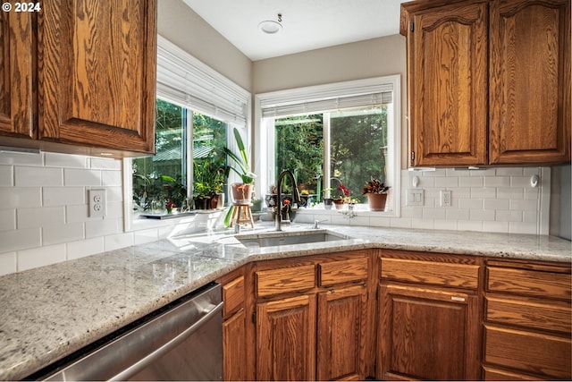 kitchen with light stone counters, dishwasher, decorative backsplash, and sink