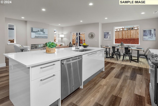 kitchen featuring stainless steel appliances, white cabinets, hardwood / wood-style flooring, sink, and an island with sink