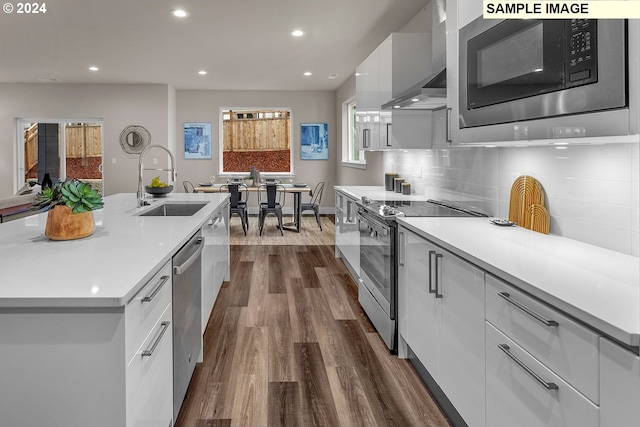 kitchen featuring stainless steel appliances, white cabinetry, sink, an island with sink, and dark wood-type flooring