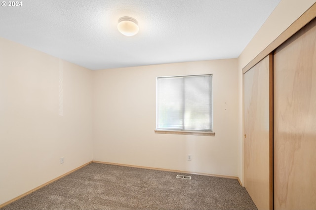 unfurnished bedroom with carpet floors, a textured ceiling, and a closet