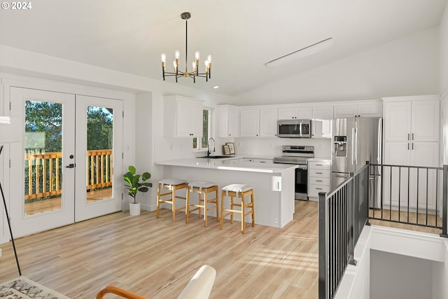 kitchen featuring a breakfast bar area, stainless steel appliances, kitchen peninsula, white cabinetry, and decorative light fixtures