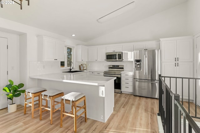 kitchen with sink, white cabinetry, a kitchen breakfast bar, kitchen peninsula, and appliances with stainless steel finishes