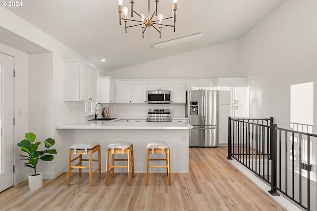 kitchen featuring stainless steel appliances, sink, white cabinetry, kitchen peninsula, and a breakfast bar area