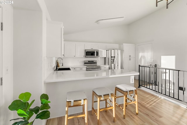 kitchen featuring kitchen peninsula, stainless steel appliances, white cabinetry, and sink