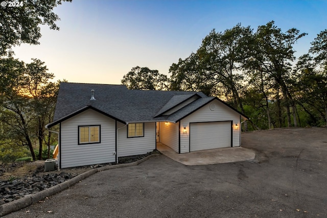 ranch-style home featuring central AC unit and a garage