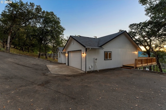 property exterior at dusk featuring a garage and a wooden deck