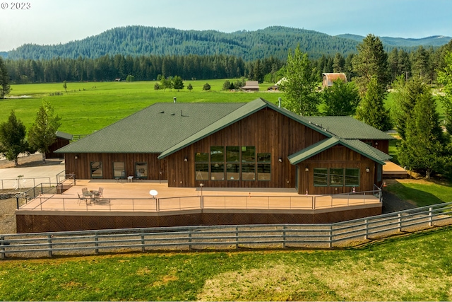 rear view of house with a patio, a rural view, a lawn, and a mountain view