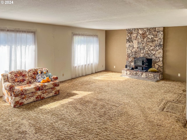 carpeted living room featuring a wood stove and a textured ceiling