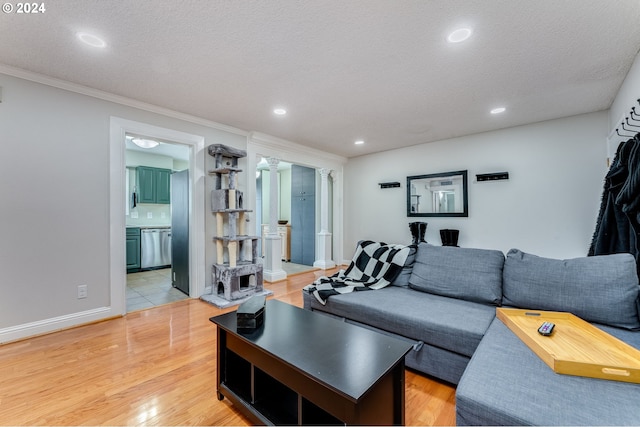 living room with a textured ceiling, crown molding, ornate columns, and light hardwood / wood-style flooring