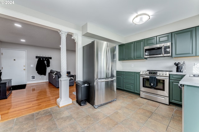 kitchen featuring stainless steel appliances, decorative columns, light tile floors, and green cabinets