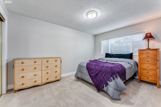 bedroom featuring a textured ceiling and light colored carpet