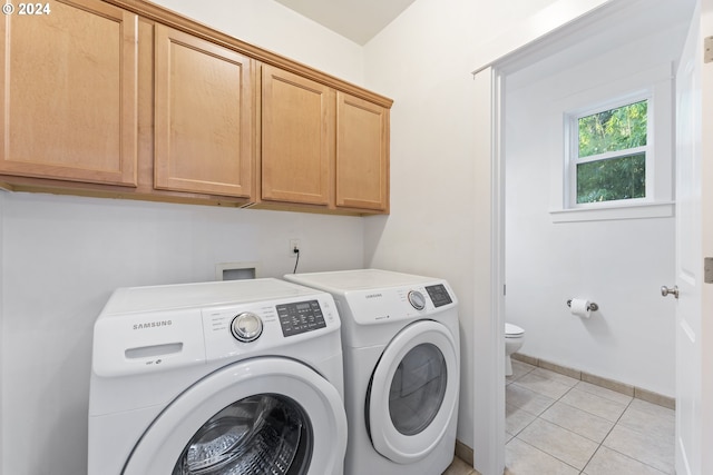 laundry area with cabinets, light tile patterned floors, and washing machine and clothes dryer