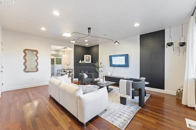 living room with a fireplace, dark wood-type flooring, and an inviting chandelier