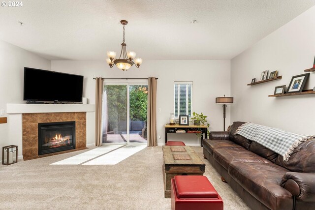 carpeted living room featuring a textured ceiling, an inviting chandelier, and a tile fireplace