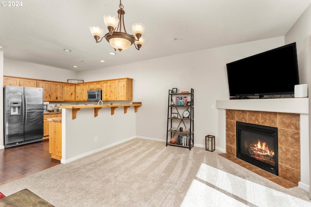 kitchen with hardwood / wood-style floors, a notable chandelier, stainless steel appliances, kitchen peninsula, and a breakfast bar