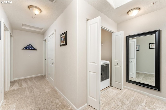 hallway featuring light colored carpet and a textured ceiling