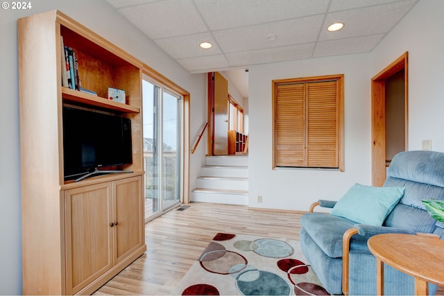 sitting room with a drop ceiling and light wood-type flooring