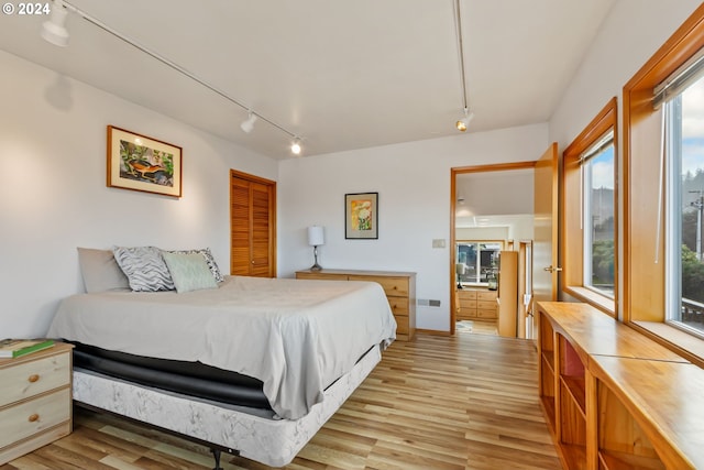 bedroom featuring a closet, light hardwood / wood-style floors, and rail lighting